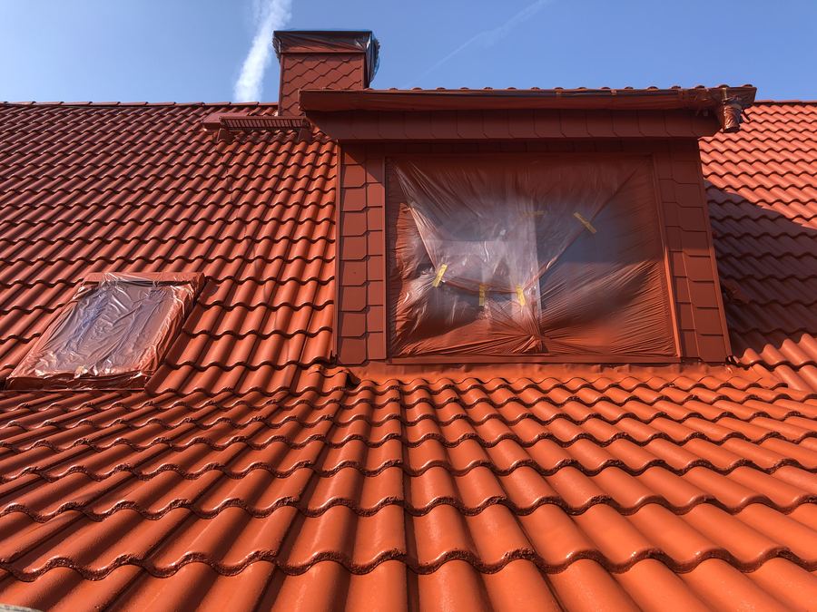 Frisch rot beschichtetes Ziegeldach, Dachfenster und Gaubenfenster mit Folie abgeklebt